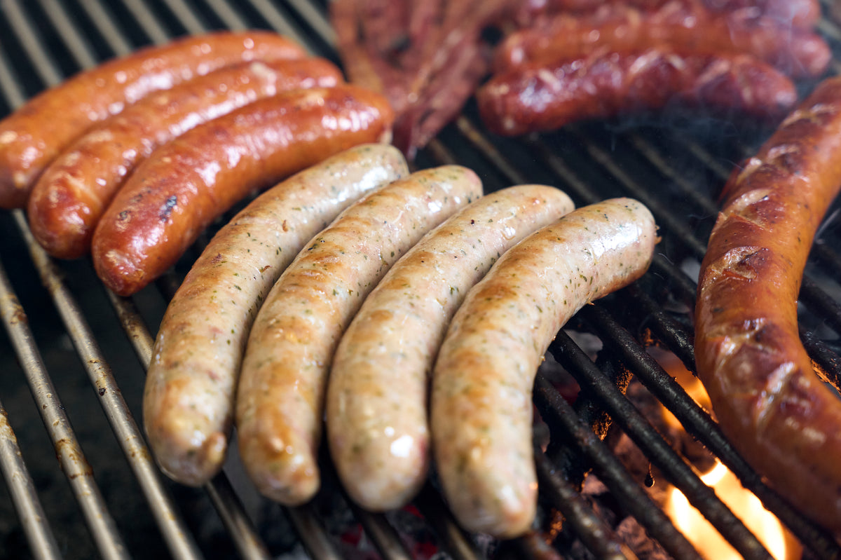 Mr Bratwurst sausages cooking on the grill